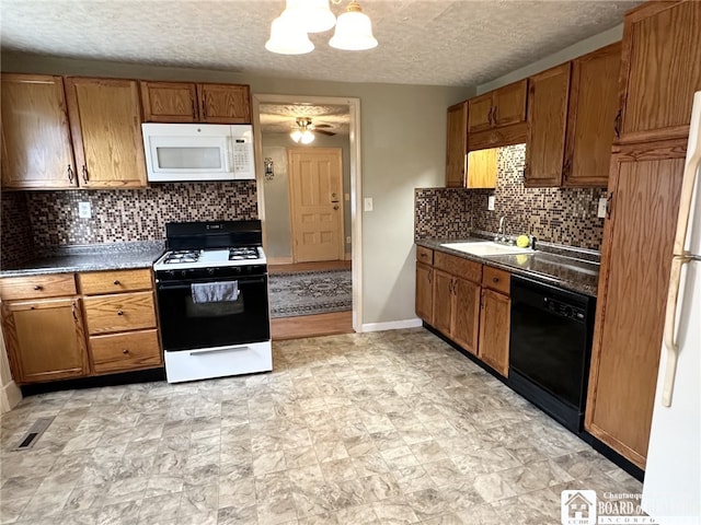 kitchen with a textured ceiling, sink, ceiling fan with notable chandelier, and white appliances