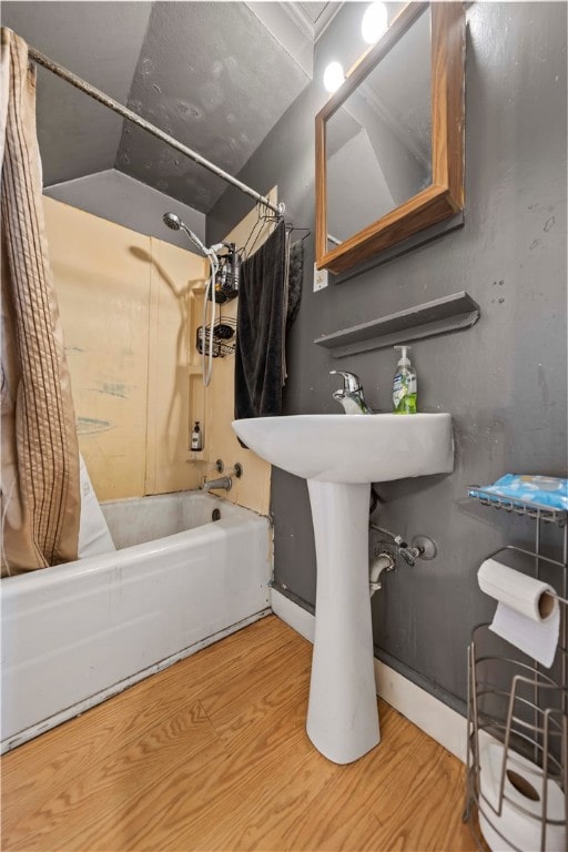 bathroom featuring shower / tub combo, hardwood / wood-style flooring, and vaulted ceiling