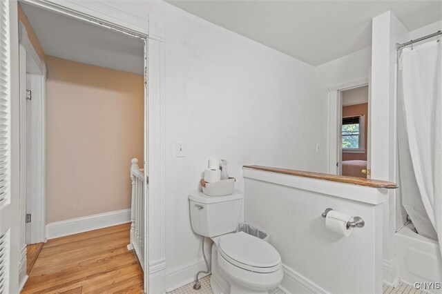 bathroom featuring hardwood / wood-style floors, shower / bath combo with shower curtain, and toilet