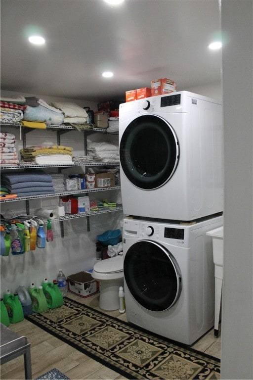 clothes washing area with stacked washing maching and dryer and light hardwood / wood-style floors