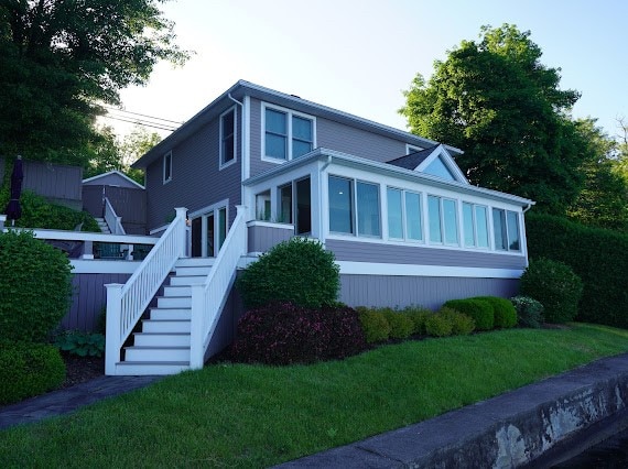 view of front of house featuring a sunroom, a front lawn, and a wooden deck