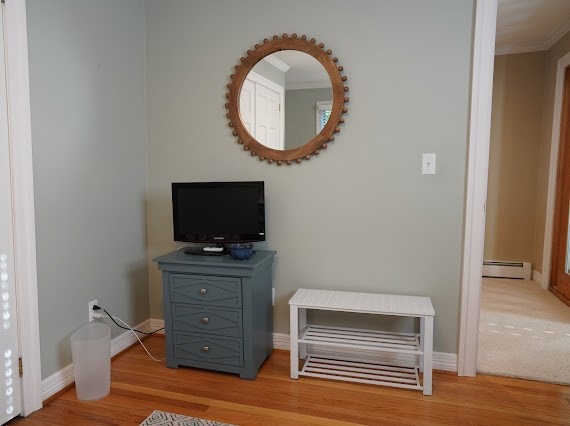 interior space featuring ornamental molding, hardwood / wood-style floors, and a baseboard radiator