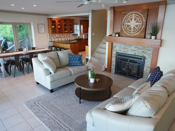 living room featuring a fireplace, ceiling fan, light tile patterned flooring, and crown molding