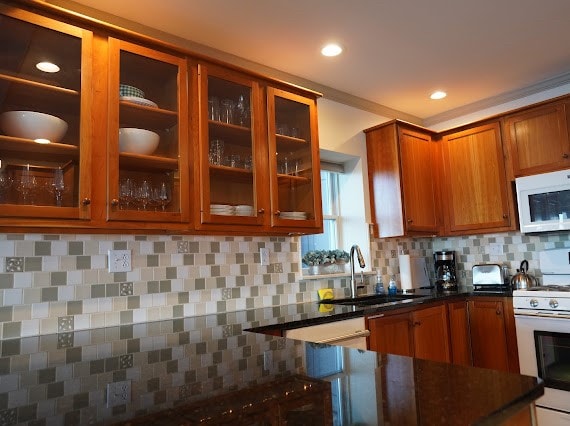 kitchen featuring backsplash, white appliances, and sink