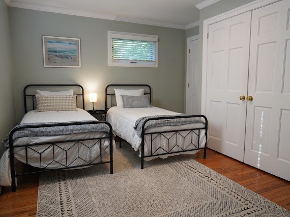 bedroom featuring a closet, hardwood / wood-style floors, and ornamental molding