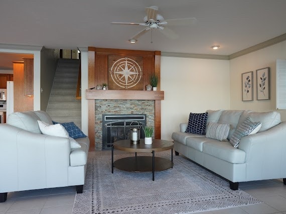 tiled living room with a fireplace, ceiling fan, and crown molding