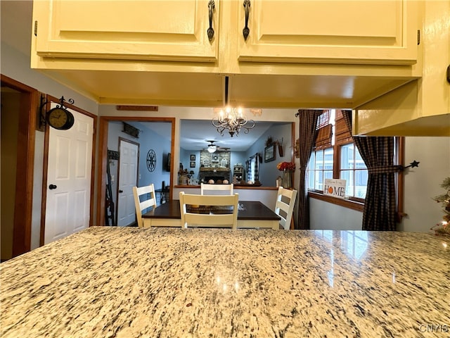 kitchen featuring hanging light fixtures, ceiling fan, and light stone countertops