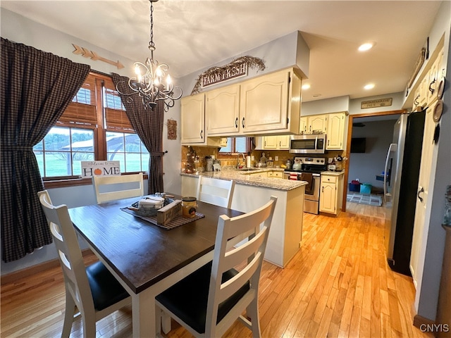 kitchen with light hardwood / wood-style floors, sink, tasteful backsplash, pendant lighting, and appliances with stainless steel finishes