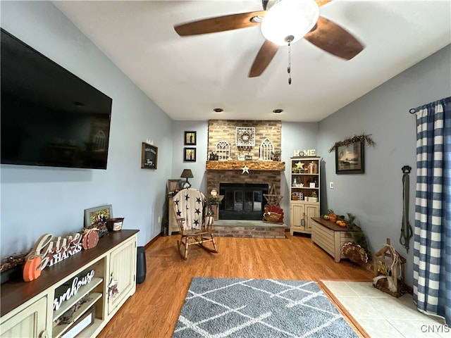 living room featuring a fireplace, light hardwood / wood-style floors, and ceiling fan