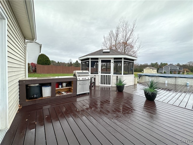 wooden terrace featuring a sunroom, a covered pool, and grilling area