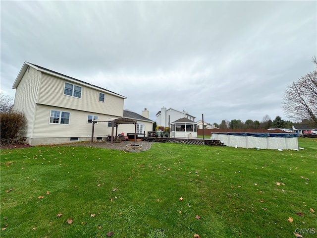 rear view of property featuring a covered pool, a yard, and a patio area