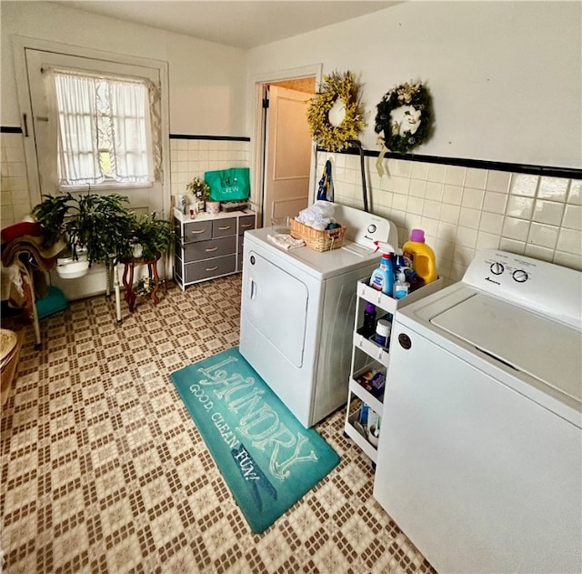 clothes washing area featuring washing machine and dryer and tile walls