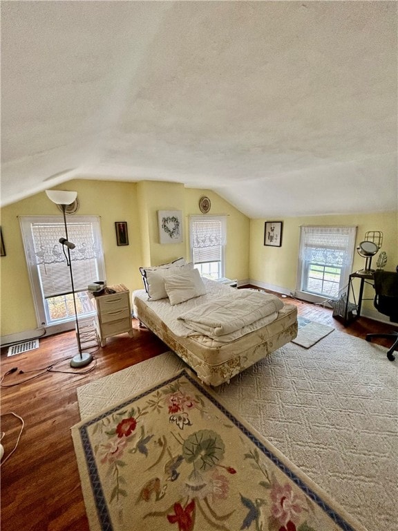 bedroom featuring a textured ceiling, hardwood / wood-style floors, and vaulted ceiling