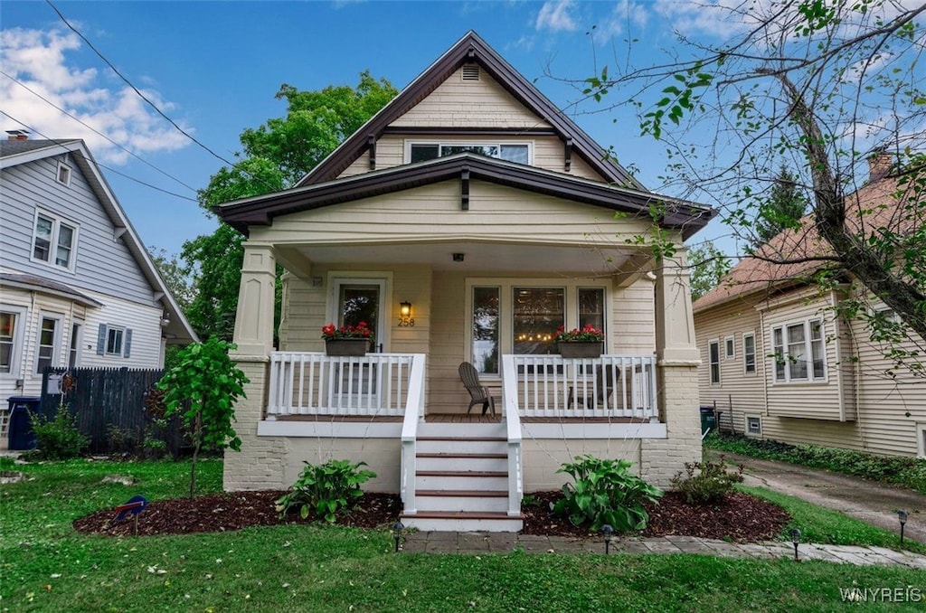 bungalow-style home with a front yard and covered porch