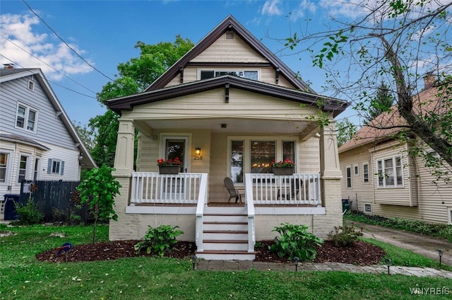 bungalow-style home with a front yard and covered porch