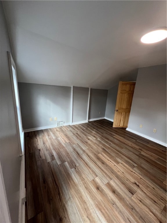 empty room featuring vaulted ceiling and hardwood / wood-style flooring