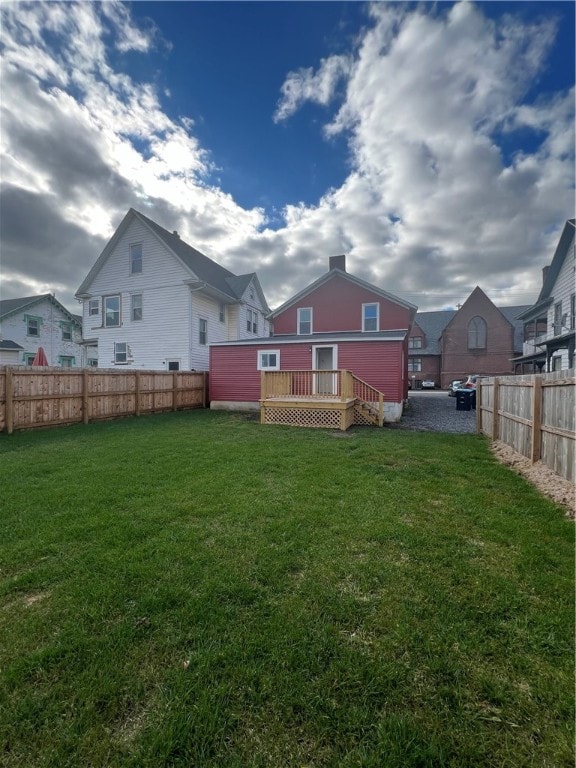 back of property featuring a lawn and a wooden deck