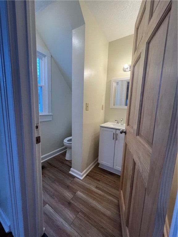 bathroom with vanity, a textured ceiling, hardwood / wood-style flooring, toilet, and lofted ceiling