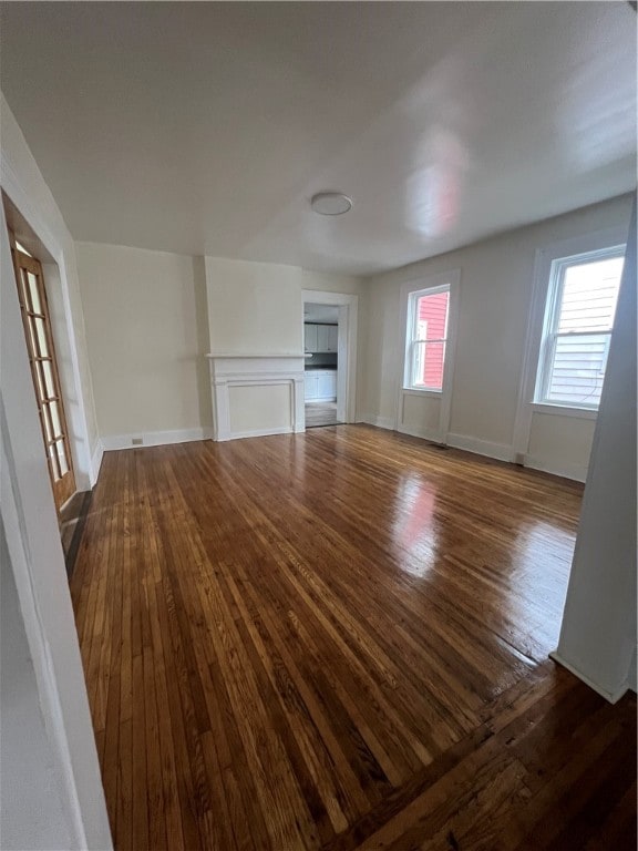 unfurnished living room featuring dark wood-type flooring and plenty of natural light