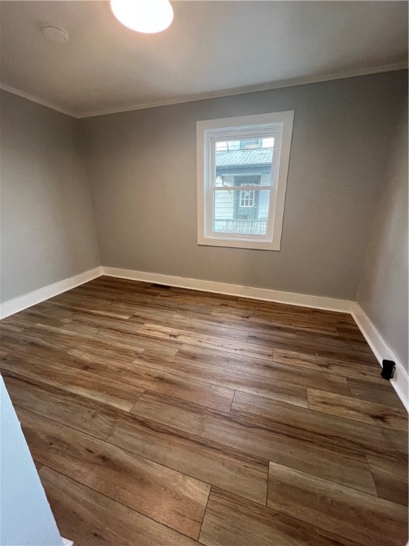 empty room with dark hardwood / wood-style floors and crown molding