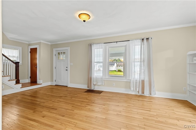 entrance foyer with ornamental molding and light hardwood / wood-style floors