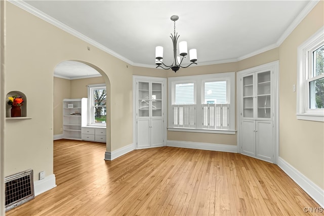 unfurnished dining area with light wood-type flooring, a notable chandelier, and crown molding