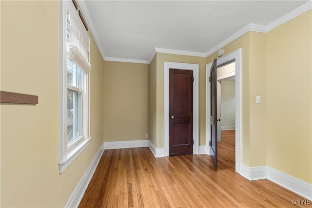 empty room featuring light wood-type flooring and crown molding