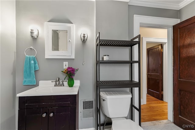 bathroom with ornamental molding, hardwood / wood-style floors, vanity, and toilet