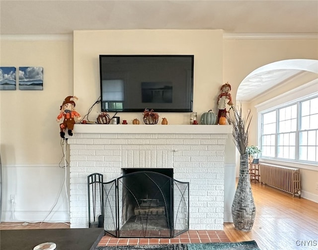 interior details with hardwood / wood-style floors, a fireplace, radiator heating unit, and crown molding