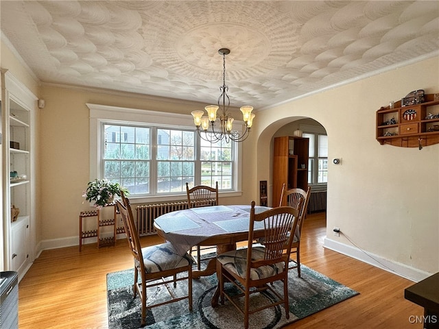 dining area with ornamental molding, an inviting chandelier, light hardwood / wood-style floors, and radiator