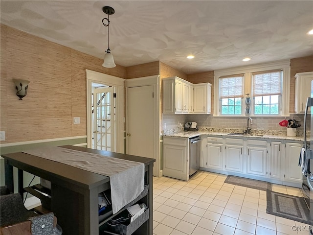 kitchen featuring white cabinetry, sink, light stone counters, hanging light fixtures, and dishwasher