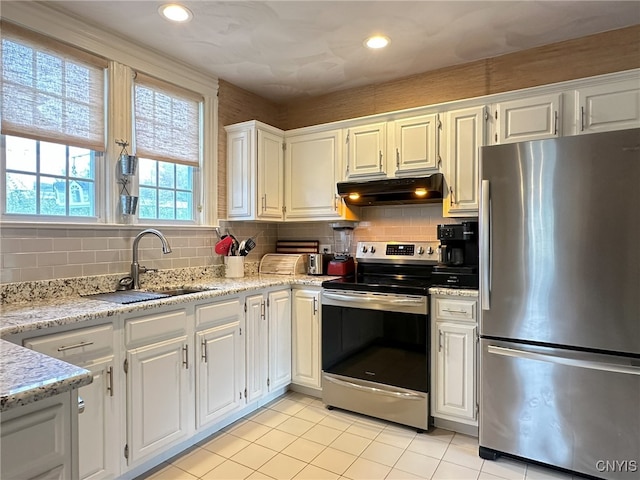 kitchen with stainless steel appliances, white cabinets, sink, and light stone counters