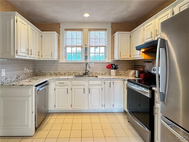 kitchen with light stone counters, stainless steel appliances, backsplash, sink, and white cabinets