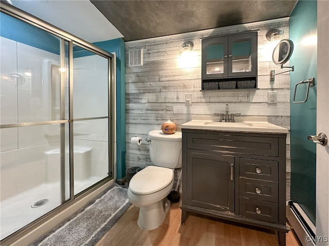 bathroom with walk in shower, vanity, wood walls, hardwood / wood-style floors, and toilet