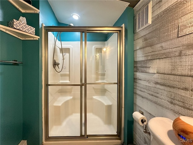 bathroom with walk in shower, wood walls, and toilet