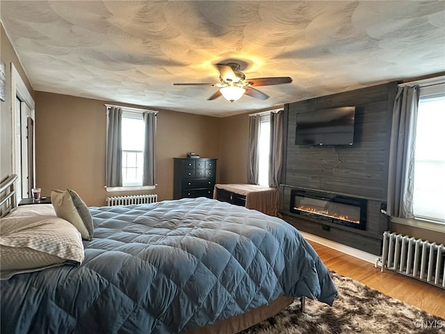 bedroom featuring radiator, multiple windows, and light hardwood / wood-style flooring