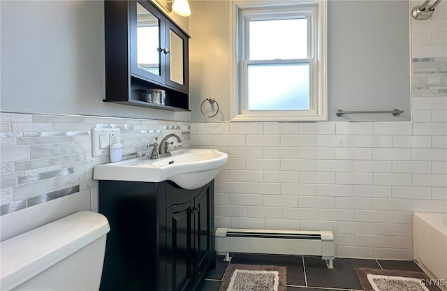 bathroom featuring tile walls, a baseboard heating unit, plenty of natural light, and vanity