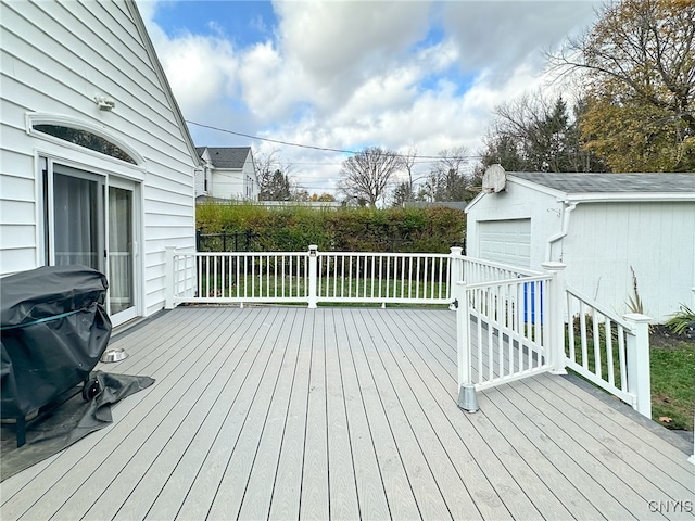 wooden terrace featuring an outbuilding, a garage, and a grill