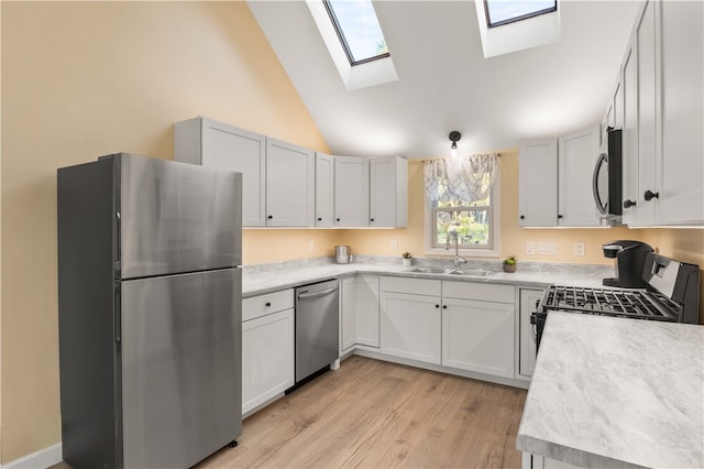 kitchen with appliances with stainless steel finishes, high vaulted ceiling, sink, light hardwood / wood-style floors, and white cabinets