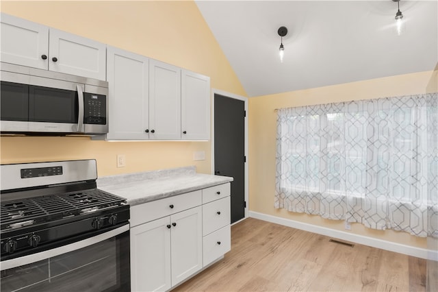 kitchen with stainless steel appliances, white cabinetry, light wood-type flooring, and lofted ceiling