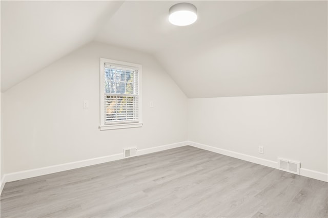 additional living space featuring light wood-type flooring and vaulted ceiling