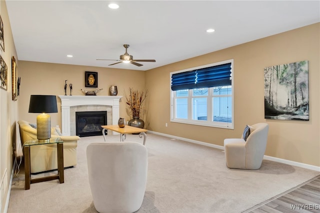 living room featuring a tiled fireplace, light carpet, and ceiling fan