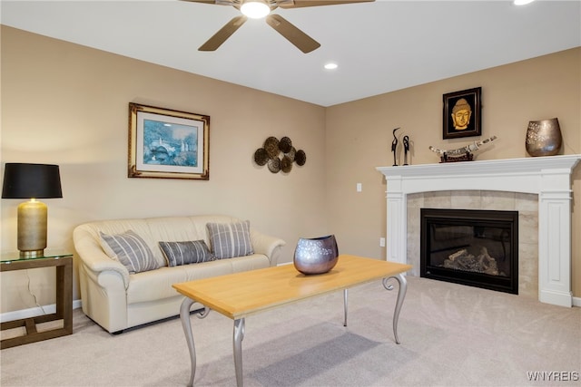 living room featuring a tiled fireplace, light colored carpet, and ceiling fan