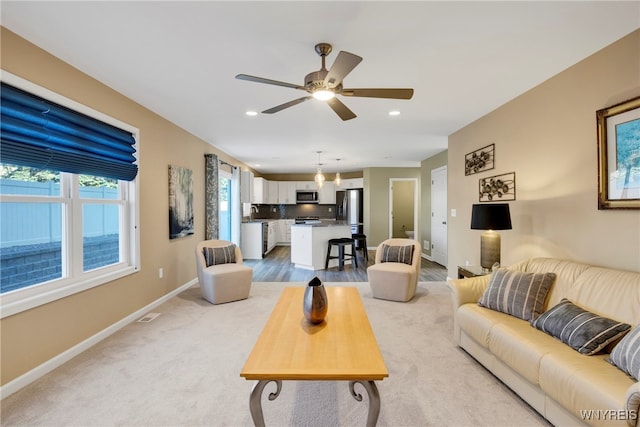 living room featuring sink, light colored carpet, and ceiling fan