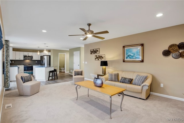 living room featuring sink, light carpet, and ceiling fan