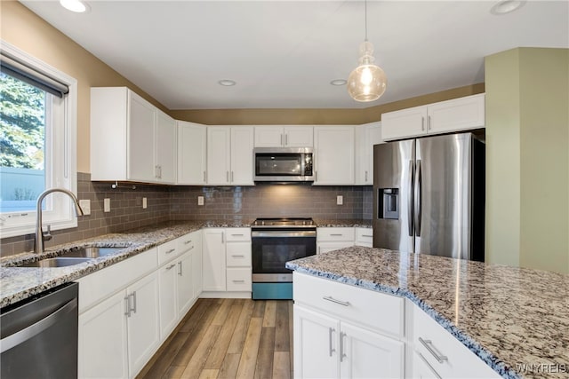 kitchen with white cabinetry, appliances with stainless steel finishes, sink, and light hardwood / wood-style flooring