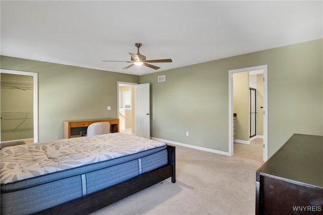 bedroom with ceiling fan, light carpet, a closet, and a walk in closet