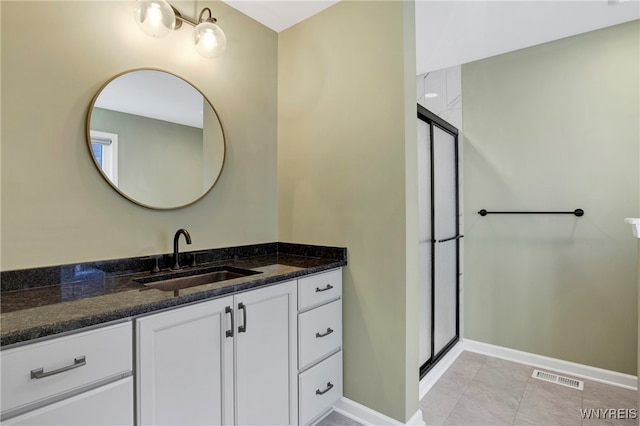 bathroom with an enclosed shower, vanity, and tile patterned flooring