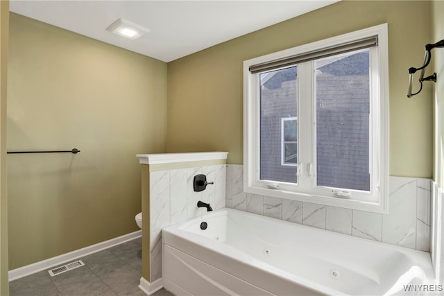 bathroom featuring tile patterned flooring, a bath, and toilet