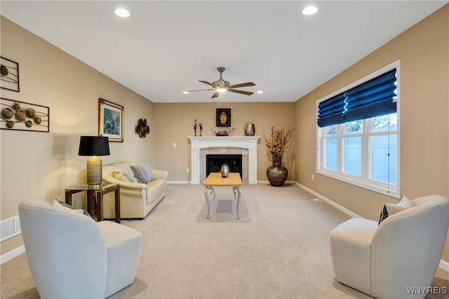 carpeted living room featuring a tiled fireplace and ceiling fan